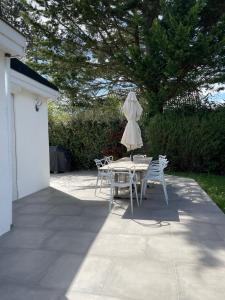 レシニーにあるMaison dans résidence américaineのパティオにテーブルと椅子と傘