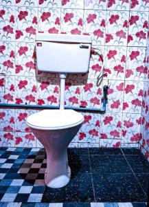 a toilet in a bathroom with red flowers on the wall at Nebula Nest Tent Camping Munnar in Munnar