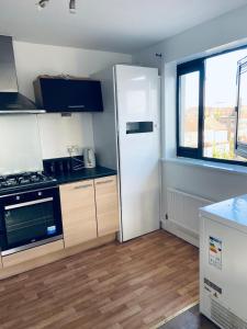 a kitchen with a white refrigerator and a window at Alba, 2 Bed Flat, by Grays Station, Free Parking in Stifford