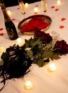 ein Tisch mit Rosen, einer Flasche Wein und Kerzen in der Unterkunft Love Room Chic Lescapade à Cherbourg in Cherbourg en Cotentin + 6 Fotos
