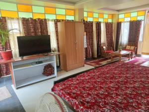 a living room with a flat screen tv and a bed at SAI´S GRACE in Kalimpong