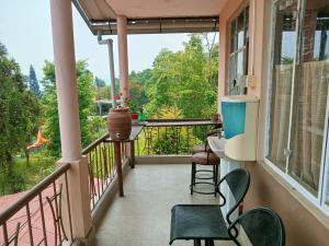 a balcony with chairs and a table and a window at SAI´S GRACE in Kalimpong