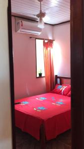 een slaapkamer met een rood bed met een rode sprei bij Kalena Suítes in Lençóis