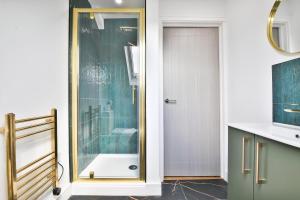uma casa de banho com um chuveiro e uma porta de vidro em North Road Luxe New Serviced Apartments- Parking Available with Full Kitchen Amenities em Cardiff