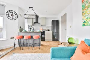 uma cozinha com um sofá azul e bancos de bar laranja em North Road Luxe New Serviced Apartments- Parking Available with Full Kitchen Amenities em Cardiff