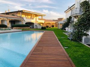una piscina en un patio con una pasarela de madera en LOTUS Wellness Apartment - Resort Ginestre - Palau - Sardinia, en Palau