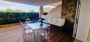 帕勞的住宿－LOTUS Wellness Apartment - Resort Ginestre - Palau - Sardinia，木甲板上的玻璃桌子和椅子