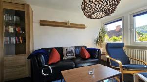 a living room with a black leather couch and a table at Stadt-Ferienwohnung mit 55 m² für 2 erw. Personen und Kind bis 3 Jahren in Bad Lauterberg