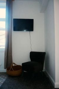 a room with a chair and a television on a wall at Au Béguinage - Studio au coeur de wavre in Wavre