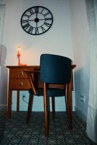 a desk with a chair and a clock on the wall at Au Béguinage - Studio au coeur de wavre in Wavre