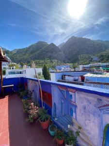 a blue building with a bench on a balcony with mountains at Hostel Aline in Chefchaouene