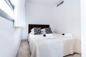 una camera da letto bianca con un letto con lenzuola e cuscini bianchi di Kook Isrentals - ApartHotels In City Center a Gerusalemme
