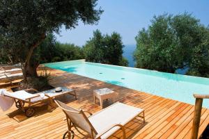 a swimming pool with two chairs and a table on a wooden deck at Rupe Alta Home in Castellabate