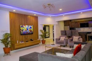 sala de estar con sofá, sillas y TV en Proof Hotel Lekki en Lagos