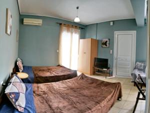 a bedroom with two beds and a television in it at Studios Akrotiri in Mytilini