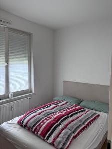 uma cama com um cobertor listrado vermelho e branco em Nexus Suites em Pulheim