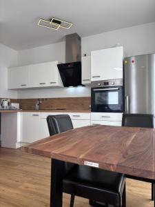 uma cozinha com uma mesa de madeira e armários brancos em Nexus Suites em Pulheim
