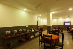 a dining room with a table and chairs and a television at Airport Hotel Ark View in New Delhi