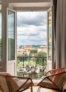 Habitación con balcón con mesa y sillas. en Sofitel Roma Villa Borghese, en Roma