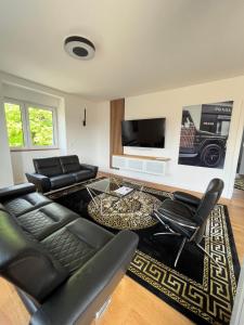 ブクステフーデにあるExklusives Penthouse in Buxtehude !!のリビングルーム(黒革の家具、薄型テレビ付)