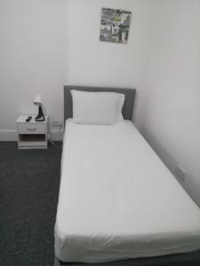 a bedroom with a white bed and a night stand at Single Room Shared bathroom Free Street Parking Near Anfield LFC in Liverpool
