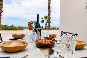 una mesa con un tazón de comida y una botella de vino en Villa Anna By Vivimy, en Salve