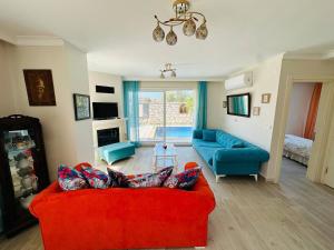 sala de estar con sofá rojo y sillas azules en Evalacati - Villa Harnup- Newly Renovated Villa, en Alacati