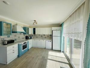 a large kitchen with white cabinets and blue appliances at Evalacati - Villa Harnup- Newly Renovated Villa in Alacati