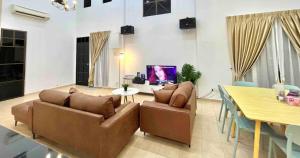 A'Famosa Bungalow*Private Garden Stage*22Pax*NEW في Kampong Ulu Pegoh: غرفة معيشة مع كنبتين وغرفة طعام