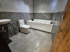 La salle de bains est pourvue d'une baignoire, de toilettes et d'un lavabo. dans l'établissement Nova Park, à Rajkot