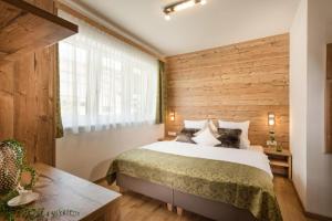 1 dormitorio con 1 cama y pared de madera en das Burghard en Altenmarkt im Pongau