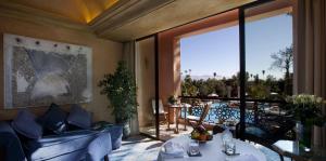 a living room with blue furniture and a large window at Es Saadi Marrakech Resort - Palace in Marrakech