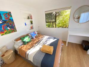 1 dormitorio con cama con espejo y ventana en Beachside Gem - Cosy Chalet, en Parapara 