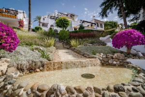 un jardín con flores rosas frente a una casa en AB2 - Aldea Blanca Marbella by Roomservices, en Marbella