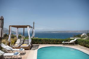 a swimming pool with chairs and a gazebo at Villa Nicolas Plaka With Sea View in Plaka