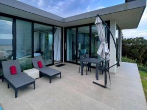 un patio extérieur avec des chaises et un parasol dans l'établissement Ntomb'lele Ocean View Luxury Holiday Villas, à Tugela Mouth