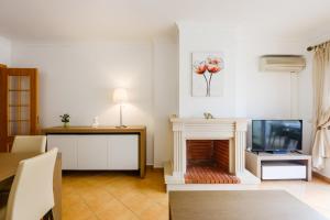a living room with a fireplace and a tv at Quinta do Paiva - Jardins do Vale in Albufeira