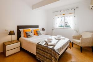 a white bedroom with a bed and a chair at Quinta do Paiva - Jardins do Vale in Albufeira