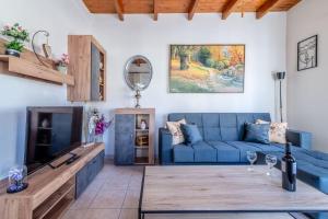 Lovely Maisonette in the village في Márathos: غرفة معيشة مع أريكة زرقاء وطاولة