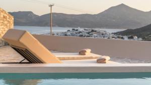 a swimming pool with a lounge chair next to the water at Solus Suites Milos in Adamas