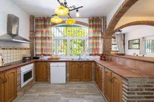 a kitchen with wooden cabinets and a large window at Villa Terrenito Private Pool by AORA STAY in Fuengirola