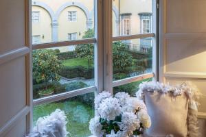 una ventana con flores blancas en el alféizar de la ventana en Casa Eleonora charming quiet apartment, en Lucca