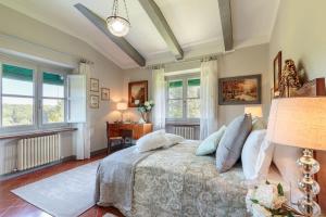 a bedroom with a bed and a desk and windows at Villa D'Amico, charming indulgence overlooking Lucca Town Centre in Lucca +59 photos