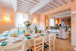 a dining room with a long table with white chairs at Casolare dei Colli, Panoramic Private Pool, Lavish Interiors and a Gourmet Kitchen in Camaiore