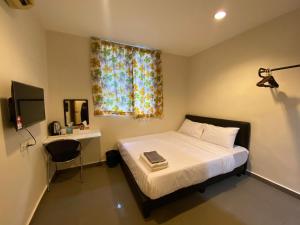 a bedroom with a bed and a desk and a window at Jb Sojourn in Skudai