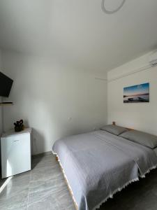 biała sypialnia z łóżkiem i telewizorem w obiekcie Room Sleep & Fly w mieście Kaštela