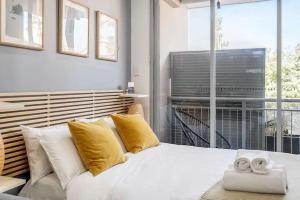 uma cama branca com almofadas amarelas num quarto com uma janela em Studio in Crown St - Private Balcony & Aircon em Sydney