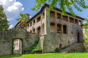 un antiguo edificio de piedra con una puerta en el césped en La Vaseria Country House with Secret Garden and pool, en Ghivizzano