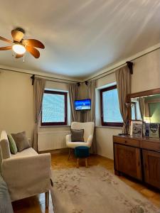 een woonkamer met een bank, een stoel en een televisie bij Guesthouse Sabine - pr` Skminc in Bohinjska Bela