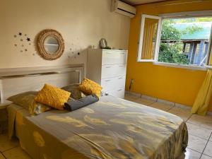 a bedroom with a bed with yellow walls and a window at La Villa Soleil in Trois Bassins